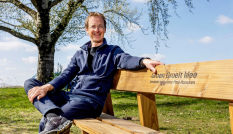 Paul Roncken zit op een bankje met het logo van Groen Groeit Mee.