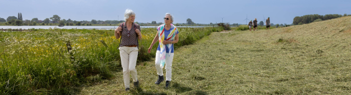 Twee vrouwen wandelen aan de voet van de Lekdijk