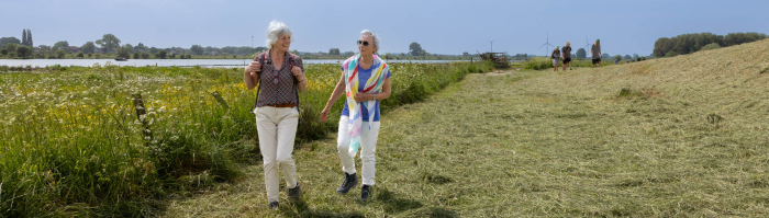 Twee vrouwen wandelen aan de voet van de Lekdijk