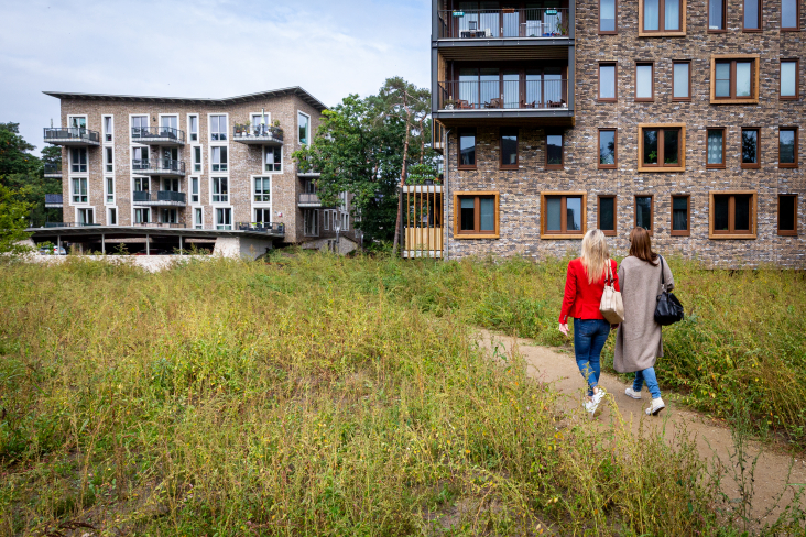 Twee vrouwen wandelen door het groen rondom lage flats