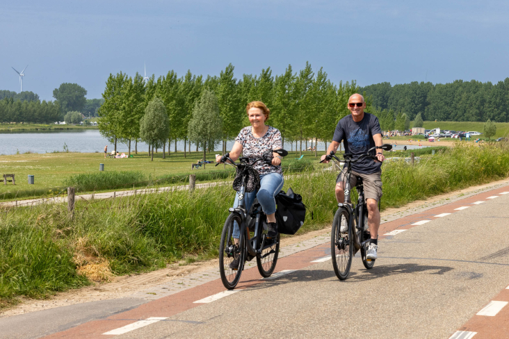 Een man en een vrouw fietsen samen op de Lekdijk