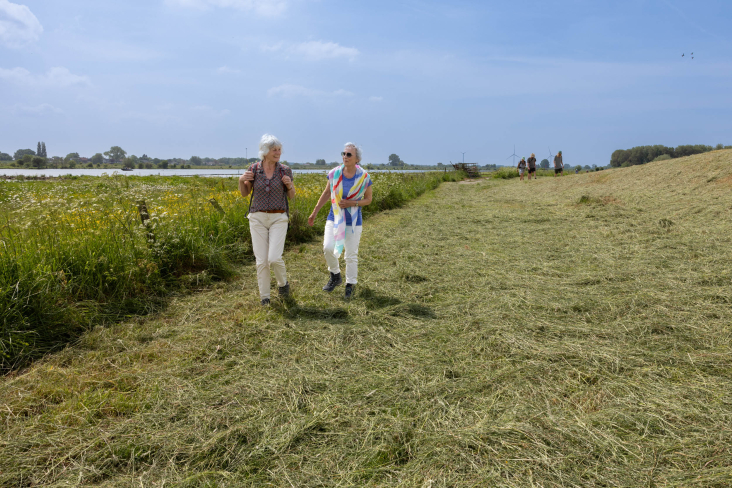 Twee vrouwen wandelen aan de voet van de Lekdijk