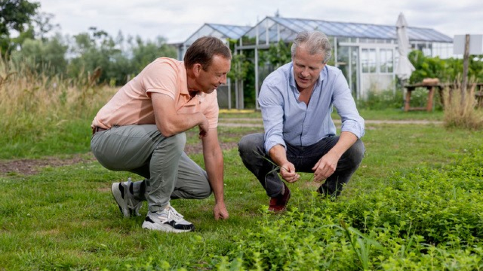 Carel Walhof en Jeroen Plesman bekijken gehurkt een stuk gras en grond