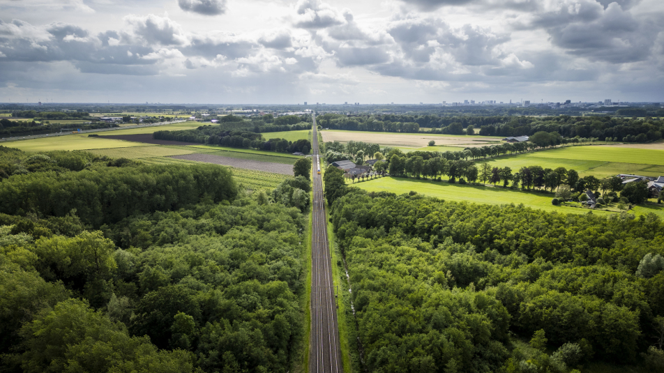 Luchtfoto van spoorlijn als barrière in het landschap